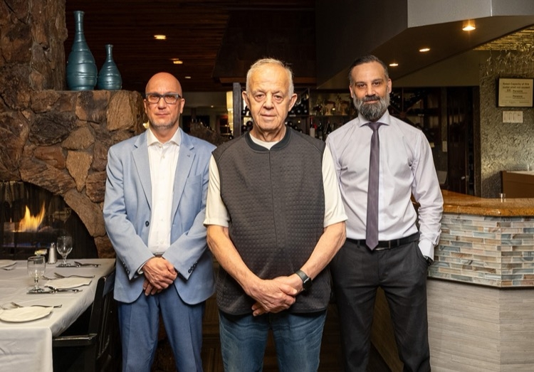 Three restaurant owners stand inside the restaurant.