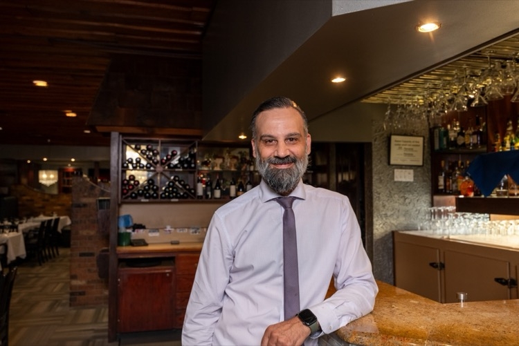 Restaurant owner smiling behind the bar inside The Cottage Restaurant.